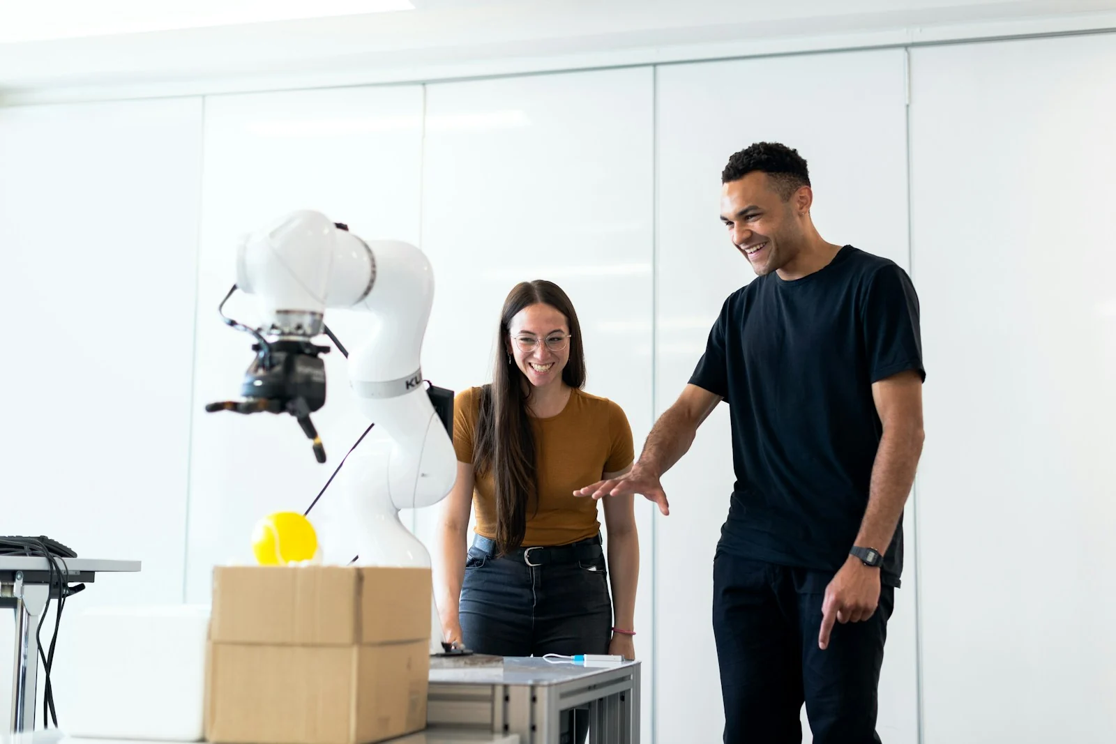 Two engineers testing a white robotic arm in a bright research laboratory